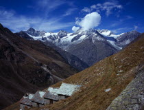 Switzerland, Zermatt, Weisshorn mountain 4506 metres with shepherd huts in foreground used for storage and shelter for climbers.