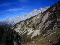 Switzerland, Bern, Gadmertal, View west along Upper Gadmertal showing third tunnels on road to Susten Pass. Gadmenflue clifftops against skyline.