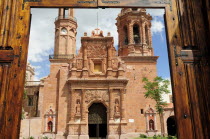 Mexico, Bajio, Zacatecas, Monastery & church of Guadalupe seen through opening in entrance gates.