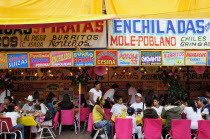 Mexico, Bajio, Zacatecas,  Feria food stalls with customers eating on tables outside.