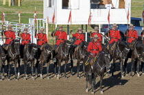 Canada, Alberta, Lethbridge, Royal Canadian Mounted Police Musical Ride, RCMP cavalry in full dress red serge uniform on horseback holding lances with red and white pennons and commanding officer with...