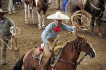 Mexico, Bajio, Zacatecas, Traditional horsemen or Charros competing in Mexican rodeo, mounted rider preparing to throw lasso.