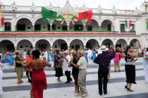 Mexico, Veracruz, Couples dancing in the Zocalo with facade of government buildings behind hung with bright decorations in the national colours for Independence Day celebrations.