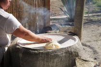Mexico, Oaxaca, Woman making tortillas outside on traditional comal griddle.