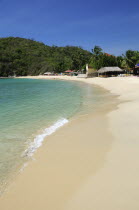 Mexico, Oaxaca, Huatulco, Bahia Santa Cruz, View along stretch of sandy beach lined by restaurants and other buildings.