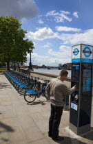 England, London, Vauxhall, Albert Embankment of the river Thames, man buying time on bicycle hire self service machine.