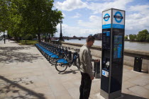 England, London, Vauxhall, Albert Embankment of the river Thames, man buying time on bicycle hire self service machine.