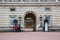 England, London, Westminster, Buckingham Palace exterior with both Queens Guard and Metropolitan Police armed officers.