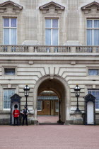 England, London, Westminster, Buckingham Palace exterior with both Queens Guard and Metropolitan Police armed officers.