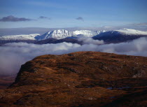 Scotland, Highlands, West, Ben More Forest and snow covered Assynt Mountains, 998 metres at highest point, above thick white cloud on skyline.  View from Knockan Crag.