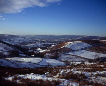 England, Derbyshire, Hathersage, View westwards over snow covered moorland landscape and fields towards Peak District village from Higgartor.