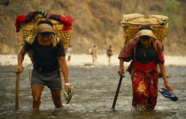Nepal, East, Arun River Valley, Porters carrying laden baskets, fording the Piluwa Khola river.