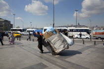 Turkey, Istanbul, Eminonu, man transporting rubbish by handcart across the square outside the NEw mosque.