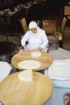 Turkey, Istanbul, Sultanahmet, woman rolling out bread dough in restaurant.