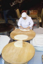Turkey, Istanbul, Sultanahmet, woman rolling out bread dough in restaurant.