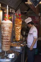 Turkey, Istanbul, Sultanahmet, man in kebab restaurant carving shawarma from skewered meats.