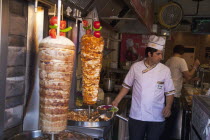 Turkey, Istanbul, Sultanahmet, man in kebab restaurant carving shawarma from skewered meats.