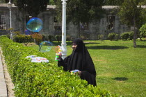 Turkey, Istanbul, Sultanahmet, woman selling bubvble gun machine in park outside the Blue Mosque.