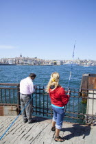 Turkey, Istanbul, Eminonu, people fishing in the Bosphorus from the quayside.