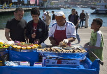 Turkey, Istanbul, Karakoy, Galata fish market, man selling freshly grilled fish served in bread roll.