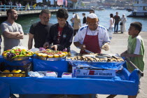 Turkey, Istanbul, Karakoy, Galata fish market, man selling freshly grilled fish served in a bread roll.