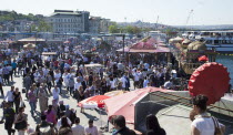Turkey, Istanbul, Eminonu, busy square with food stall on the Golden Horn next to Galata Bridge.