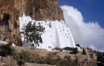 Greece,  Aegean Islands, Amorgos, Moni Chozoviotissa.  Exterior of white painted Byzantine monastery built above terraces on side of steep cliff.