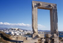 Greece, Aegean Islands, Cyclades, Naxos.  Ruins of temple and the Portara Gateway, marble doorway framing view of white painted Naxos Town below.