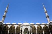 Turkey, Istanbul, Sultanahmet Camii, The Blue Mosque Courtyard with Ablutions Fountain and domed arches beneath two minarets.