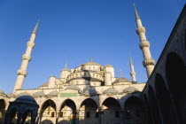 Turkey, Istanbul, Sultanahmet Camii, The Blue Mosque domes seen from the Courtyard with Arabic text from the Koran in green and the Absolution Fountain in the foreground.