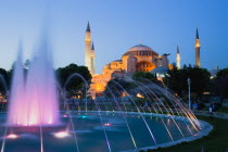 Turkey, Istanbul, Sultanahmet, Haghia Sophia and water fountain in gardens illuminated at sunset with son et lumiere light show.