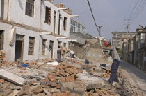 China, Jiangsu, Qidong, Demolition workers using hammers with flexible handles to demolish old residential buildings.