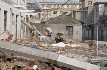 China Jiangsu Qidong; Female and male demolition workers in straw hats using hammers with flexible handles to demolish old residential buildings to make way for new construction.