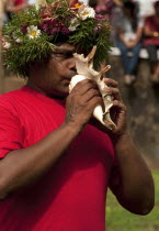 India, Goa, Sillim, San Jao Festival celebrated flower head wreaths, man blowing conch shell.