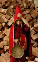India, Sikkim, Student Buddhist Lama Monk carrying a gong and preparing for a Losar procession.