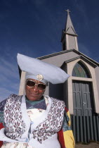 Namibia, Herero woman in Mondesa, the township of Walvis Bay, Namibia, standing next to a Presbytarian church.