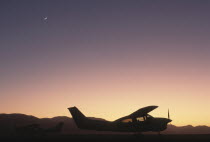Namibia, North, A cessna aircraft in the desert silhouetted at sunset.
