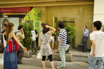 Japan, Tokyo, Ginza district, smoking station outside Shibuya JR station, smokers using designated street smoking area.