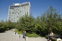 USA, New York, Manhattan, West Side, High Line Park, people realaxing  along the benches around 13th street with the Standard Hotel  in the background.