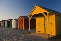 England, West Sussex, West Wittering, Sunlit beach huts at sunset on East beach.