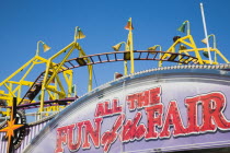 England, Lincolnshire, Skegness, Facade of amusement arcade with rollercoaster behind in clear blue sky.