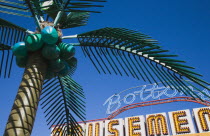 England, Lincolnshire, Skegness, Plastic artificial Palm Tree with amusement arcade  behind in clear blue sky.