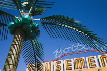 England, Lincolnshire, Skegness, Plastic artificial Palm Tree with amusement arcade  behind in clear blue sky.