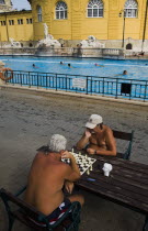 Hungary, Budapest, Pest, Bathers playing chess in summer at Szechenyi thermal baths, largest in Europe.