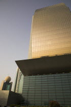UAE , Dubai,  Curved glass facade of National Bank of Dubai building with Etisalat tower behind