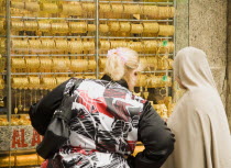 UAE , Dubai, Women, one veiled, shop for gold jewellery in window display of Gold Souk Deira.