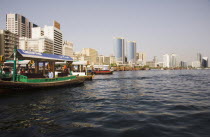 UAE , Dubai, Abra water taxi moored on the Creek with Twin Towers shopping mall and skyline behind.