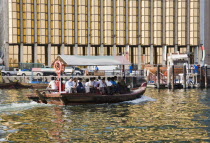 UAE , Dubai, Abra water taxi taking commuters across the Creek with bank facade behind.