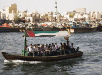 UAE , Dubai, Abra water taxi with commuters crossing the Creek Souk market behind.