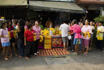 Thailand, Bangkok, Women in front of Guanyin female Goddess of Mercy statue with offerings for parade celebrating local temple.